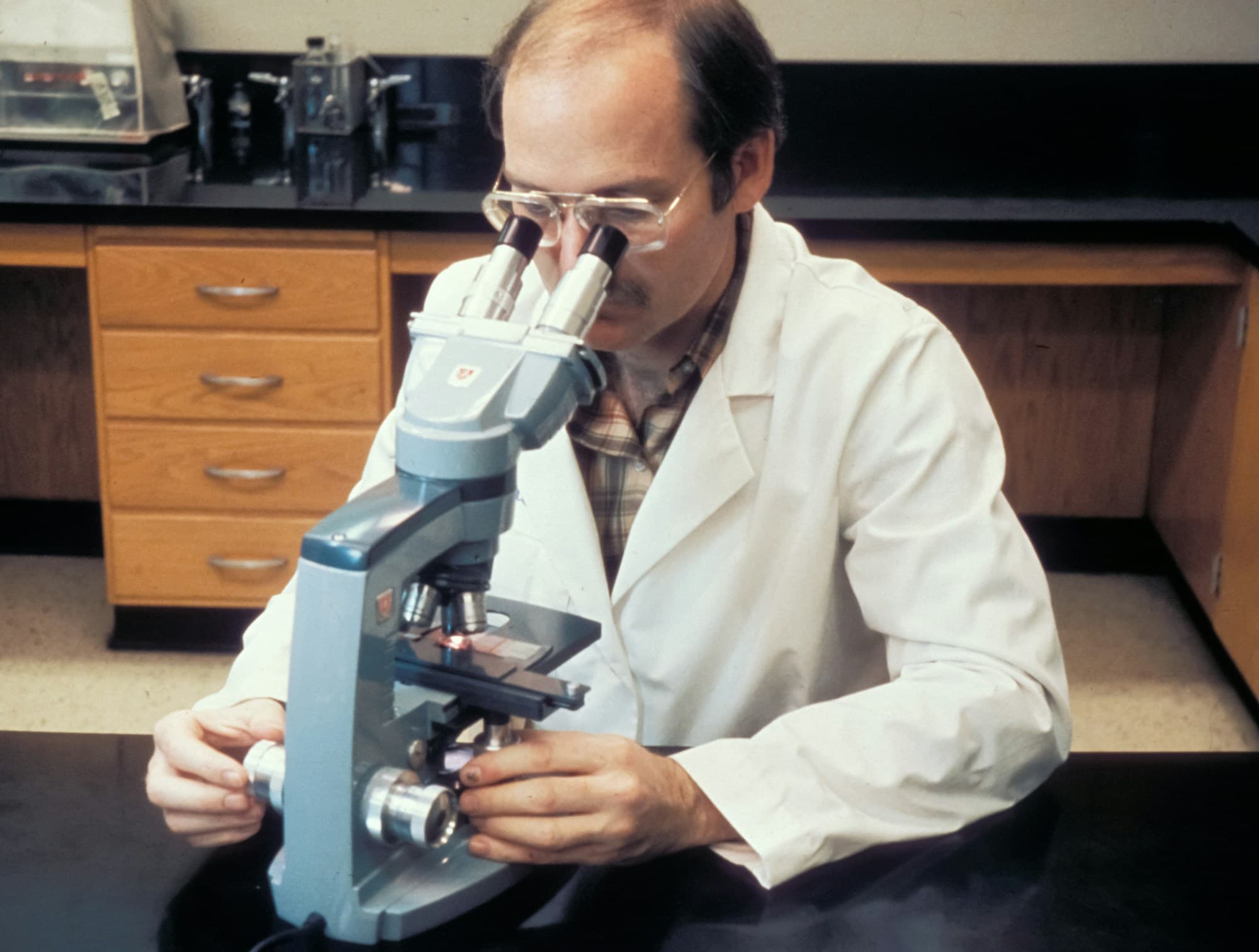 Researcher reviewing clinical data through a microscope
